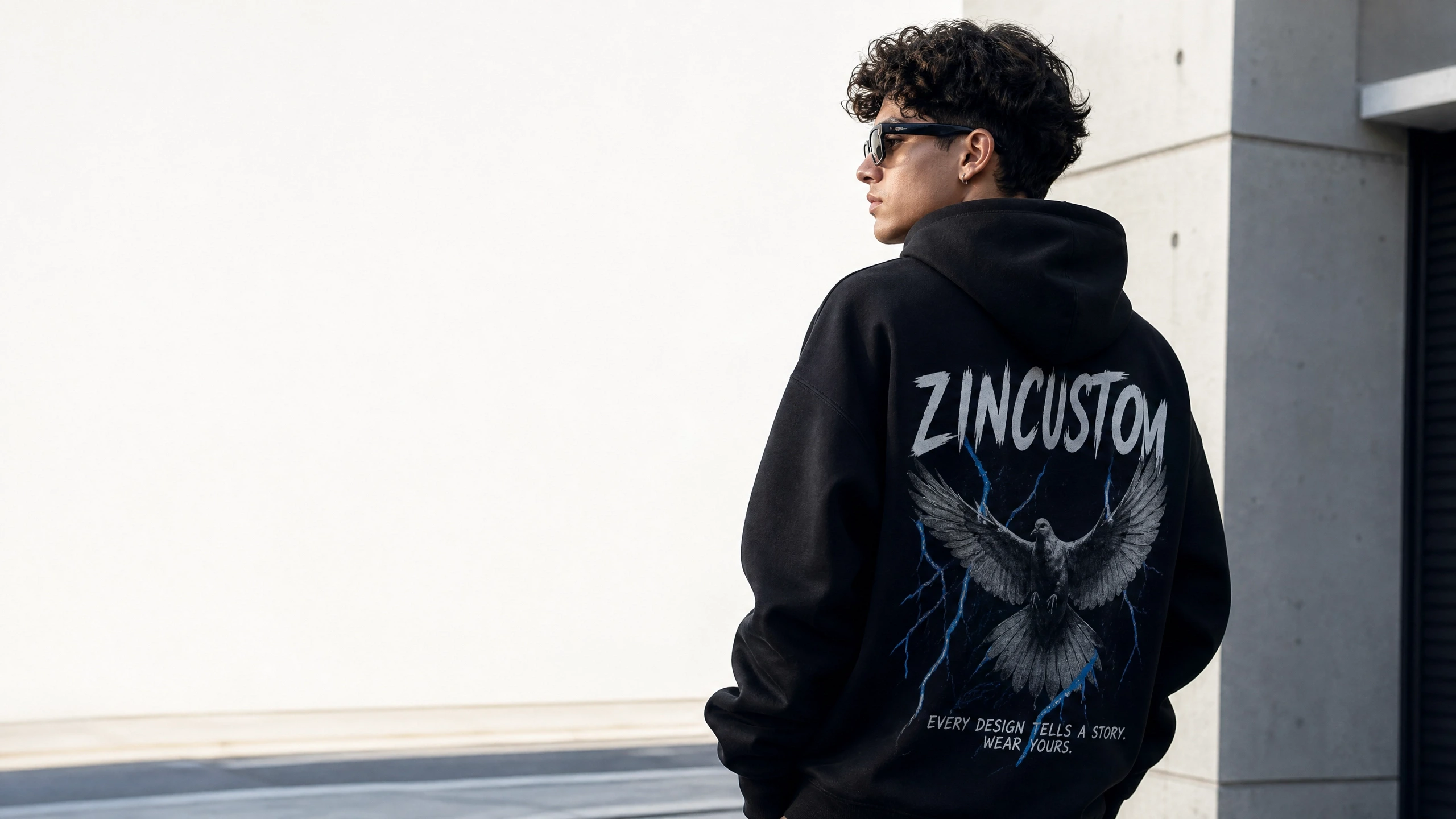 Stylish young man wearing a premium black custom hoodie from zincustom with a unique graphic eagle print in a modern urban setting.
